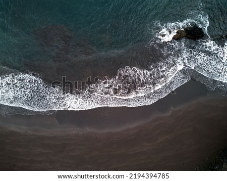 An aerial shot of beautiful waves on the black sand of Seixal Beach on Madeira