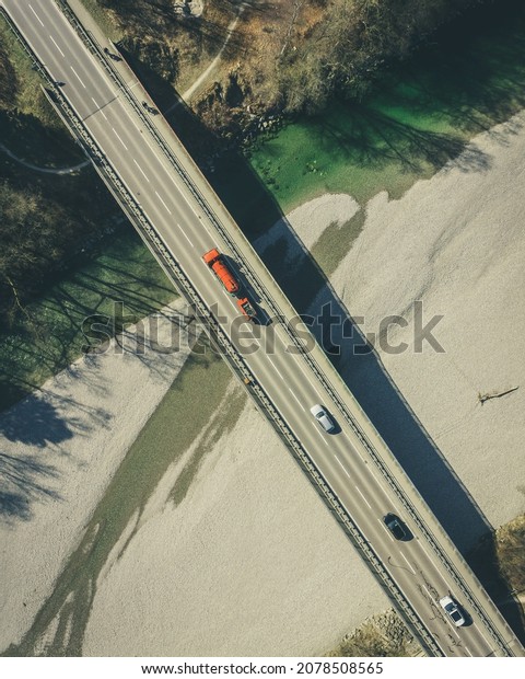 An aerial shot of a bridge with an asphalt road\
that goes over a landscape
