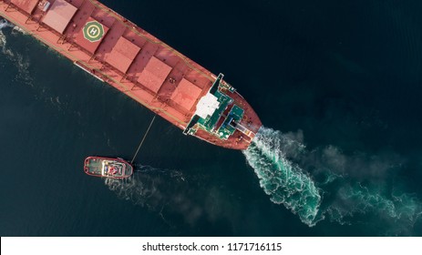 Aerial shot of a cargo ship approaching port with help of towing ship - Shutterstock ID 1171716115