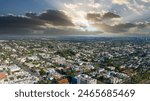 an aerial shot of the cityscape of the City of Santa Monica with vast miles of building and palm trees with majestic mountain ranges and powerful clouds at sunset in Santa Monica California USA