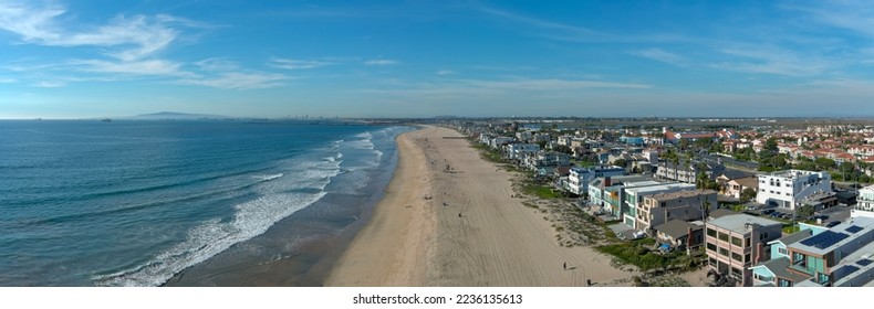 aerial shot of the coastline with blue ocean water and homes along the sand on the beach, cars driving on the street and blue sky with clouds in Huntington Beach California USA - Shutterstock ID 2236135613