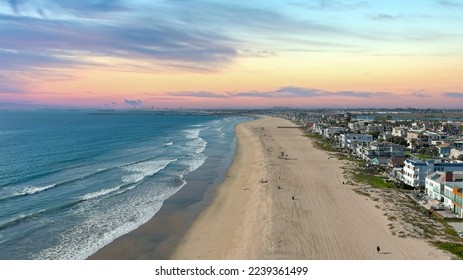 aerial shot of the coastline with blue ocean water and homes along the sand on the beach, cars driving on the street and blue sky with clouds in Huntington Beach California USA - Shutterstock ID 2239361499