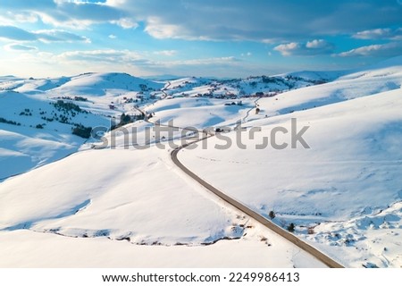 Aerial shot of empty road and frozen mountain creek in winter landscape at Zlatibor, Serbia