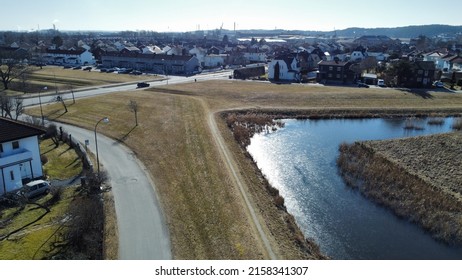 An Aerial Shot Of A Field Beside A Lake In A Residential Neighborhood