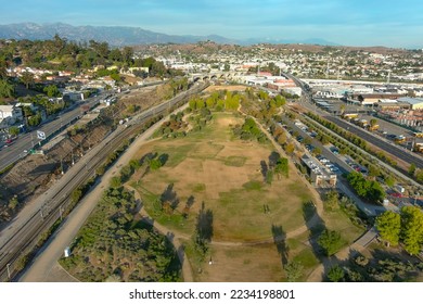 aerial shot gorgeous autumn landscape at Los Angeles State Historic Park surrounded by streets with cars driving and hillsides covered homes with blue sky and clouds in Los Angeles California