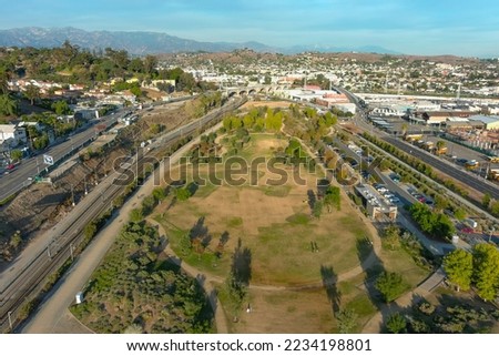 aerial shot gorgeous autumn landscape at Los Angeles State Historic Park surrounded by streets with cars driving and hillsides covered homes with blue sky and clouds in Los Angeles California