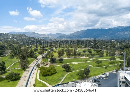 aerial shot of a gorgeous spring landscape at Brookside Golf Course with lush green trees, grass and plants, majestic mountain ranges, blue sky and clouds in Pasadena California USA
