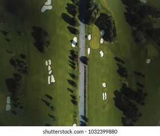 Aerial Shot Of A Green Gold Course With A Road  Splinting It In Half