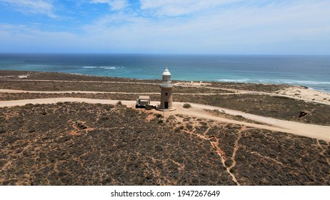 Aerial shot of high old historical lighthouse at a hill next to Indian Ocean near Exmouth, Western Australia