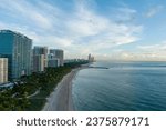 aerial shot of hotels, luxury condos and skyscrapers along the coastline at sunrise at Bal Harbour Beach, blue ocean water, silky sand and lush green trees and grass in Miami Beach Florida USA