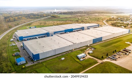 Aerial Shot Of Industrial Warehouse. Loading Hub And Many Trucks With Cargo Trailers. Aerial View Of Goods Warehouse. Modern Distribution Center From Outside. Aerial View Of Warehouse With Trucks. 