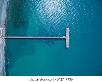 Aerial Shot Of Jetty Extending Over Crystal Water Lagoon