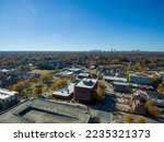 an aerial shot of the office buildings, apartments, red and yellow autumn trees, lush green trees, in the city skyline and cars driving on the street with a clear blue sky in Decatur Georgia USA
