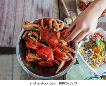 Aerial Shot Of A Plate Of Crabs Served In A Bowl With One Hand That Will Take A Fat Leg