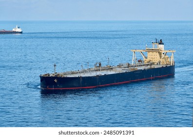 Aerial shot, port side forward view of a laden very large crude carrier, VLCC tanker with long bridge wings on the move along the strait.