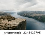 An aerial shot of the Preikestolen rocky cliff overlooking a tranquil fjord in Norway.