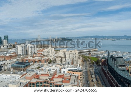 aerial shot of the San Francisco Oakland Bay Bridge, Oracle Park and office buildings and skyscrapers in the city skyline and blue ocean water in San Francisco California USA
