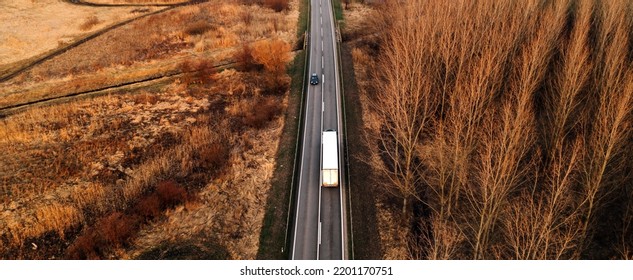 Aerial Shot Of Semi Truck And Car Driving Along The Highway Through Autumn Scenery Landscape, Drone Pov High Angle View