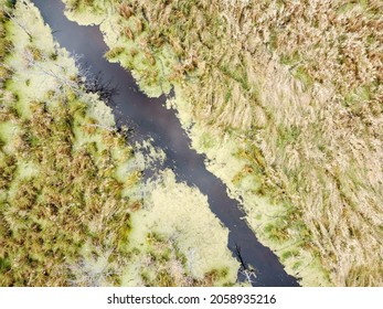 Aerial Shot Of A Small Stream Running Through A Grassy Field 