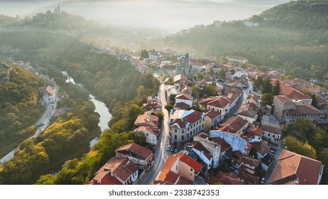 Aerial shot of sunny slightly foggy morning in Veliko Tarnovo, Bulgaria. Flying over old houses, Ascension Cathedral and river in the canyon in Veliko Tarnovo 2