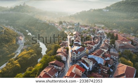 Aerial shot of sunny slightly foggy morning in Veliko Tarnovo, Bulgaria. Flying over old houses, Ascension Cathedral and river in the canyon in Veliko Tarnovo 2