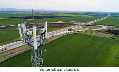 Aerial shot of telecommunication tower with highway on the back. Telecom tower antennas and satellite transmits the signals of cellular 5g 4g 3g lte mobile signals to the consumers and smartphones.