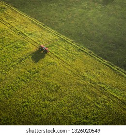 Aerial shot of tractor on the agricultural field sowing. Red tractors working on the agricultural field with sprayer. - Shutterstock ID 1326020549