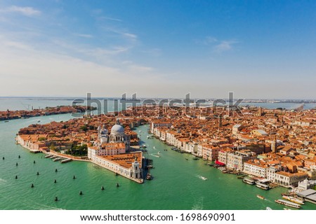Aerial shot of Venice city and Grand Canal, Italy. View from above. Tiled roofs and nerros streets. Venetian atmosphere. Blue sky and lagoon water. Historical buildings.