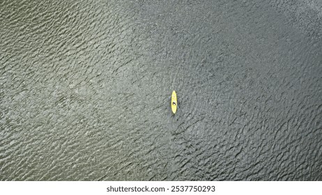 Aerial shot of a vibrant yellow kayak gliding through the clear, calm waters of a serene lake. The smooth water surface contrasts with the bright kayak, capturing the essence of adventure and nature. - Powered by Shutterstock