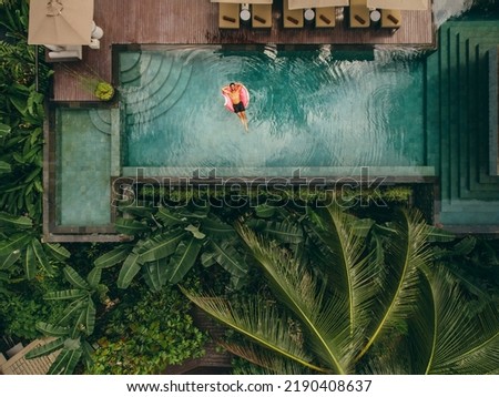 Aerial shot of young man relaxing in resort swimming pool. Male on inflatable ring in pool.