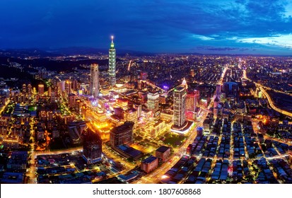 Aerial skyline of Downtown Taipei at sunset, the vibrant capital of Taiwan, with 101 Tower standing out among modern skyscrapers in Xinyi Commercial district & city lights dazzling under twilight sky