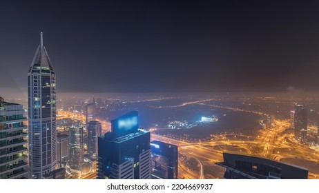 Aerial Skyline With Golf Club, Hotels And Residential Areas Far Away In Desert In Dubai During All Night Timelapse With Fog, UAE, Top View From Dubai Marina Skyscrapers. Lights Turning Off