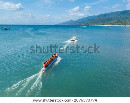 Aerial of a speedboat towing a banana boat near the beach. In Laiya, San Juan, Batangas, Phillipines.