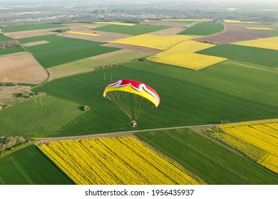 Sport aérien : Paramoteur coloré vu du ciel au-dessus des champs de colza de colza jaune au printemps. Département de l'Essonne, région Ile-de-France, France