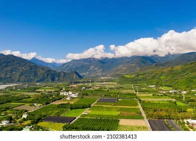 Aerial of square, green green paddy, trees and mountain with blue sky and cloud under sunny day in Longtian Village, Luye township, Taitung. A famous country with Checkerboard street, Japanese shrine. - Shutterstock ID 2102381413