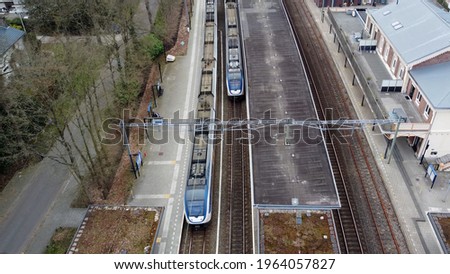 Aerial static picture of small railway station train arriving at site showing the passenger platform on the left and the public terminal building on the right