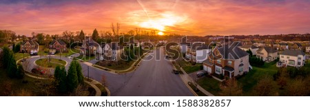 Aerial sunset panorama view of luxury upscale residential neighborhood gated community street in Maryland USA, American real estate with single family homes brick facade colorful sky cul-de-sac
