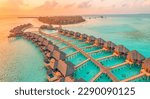 Aerial sunset panoramic landscape luxury tropical resort water villas. Beautiful island beach orange sunrise sea sky. Amazing bird eyes panorama Maldives paradise  tropical bay. Exotic summer vacation