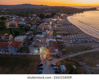 Aerial sunset view of a coastal village with beach, buildings, and cars. - Powered by Shutterstock