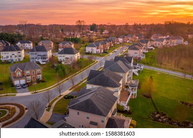 Aerial Sunset View Of Luxury Upscale Residential Neighborhood Gated Community Street In Maryland USA, American Real Estate With Single Family Homes Brick Facade Colorful Sky