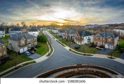 Aerial Sunset View Of Luxury Upscale Residential Neighborhood Gated Community Street In Maryland USA, American Real Estate With Single Family Homes Brick Facade Colorful Sky