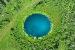 Aerial Top Down Amazing Lake Of Round Shape. Cloudy Sky Reflected In Clear Turquoise Water Of Pond Surrounded By Trees And Plants. Ripple On Water Surface, Windy Sunny Summer Day