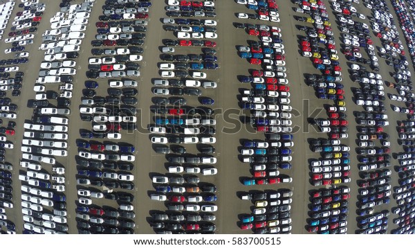 Aerial top down bird view of new car storage
parking lot showing imported new vehicles or ready to export new
automobiles storage facility car industry for American and European
market for car sales