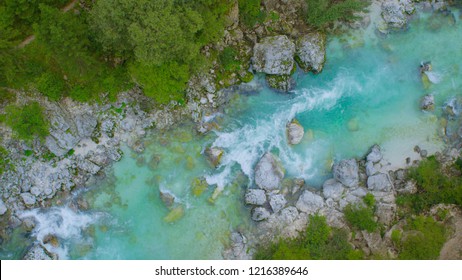 AERIAL, TOP DOWN: Breathtaking Mountain Stream Rushing Through The Lush Green Forest In Slovenia. Powerful Turquoise Colored River Flowing Down A Mountain. Crystal Clear Water Powering Over Rocks.