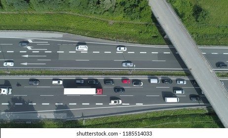 AERIAL, TOP DOWN: Cars And Trucks Drive Through A Congestion Forming Under The Concrete Overpass. Flying Above The Busy Highway On A Sunny Day. Commuters And Travelers Driving Up And Down Asphalt Road