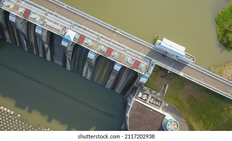 Aerial Top Down Drone Above Bendungan Sampean Baru In Java, Indonesia. Shot Over A Water Dam Reservoir With Asphalt Road Bridge Above Hydroelectric Ecology Renewable Energy With A Concrete Structure