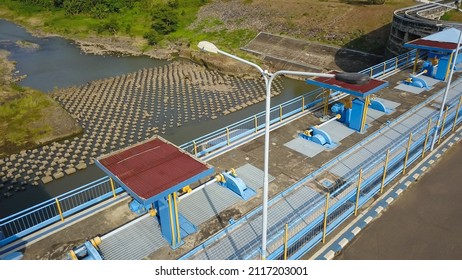 Aerial Top Down Drone Above Bendungan Sampean Baru In Java, Indonesia. Shot Over A Water Dam Reservoir With Asphalt Road Bridge Above Hydroelectric Ecology Renewable Energy With A Concrete Structure