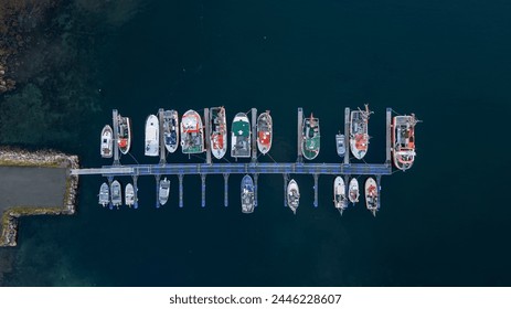 Aerial top down drone photo of a fishing dock or pier filled with boats and small ships on the small island fishing town of Husøy on Senja, Norway.   - Powered by Shutterstock