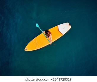 Aerial Top down drone shot of girl at yellow stand up paddle boards SUP in lake Kapchagay in Kazakhstan at sunset. - Powered by Shutterstock