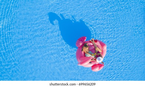 AERIAL TOP DOWN: Man And Woman Sipping Cocktails On Fun Flamingo Floatie In Pool